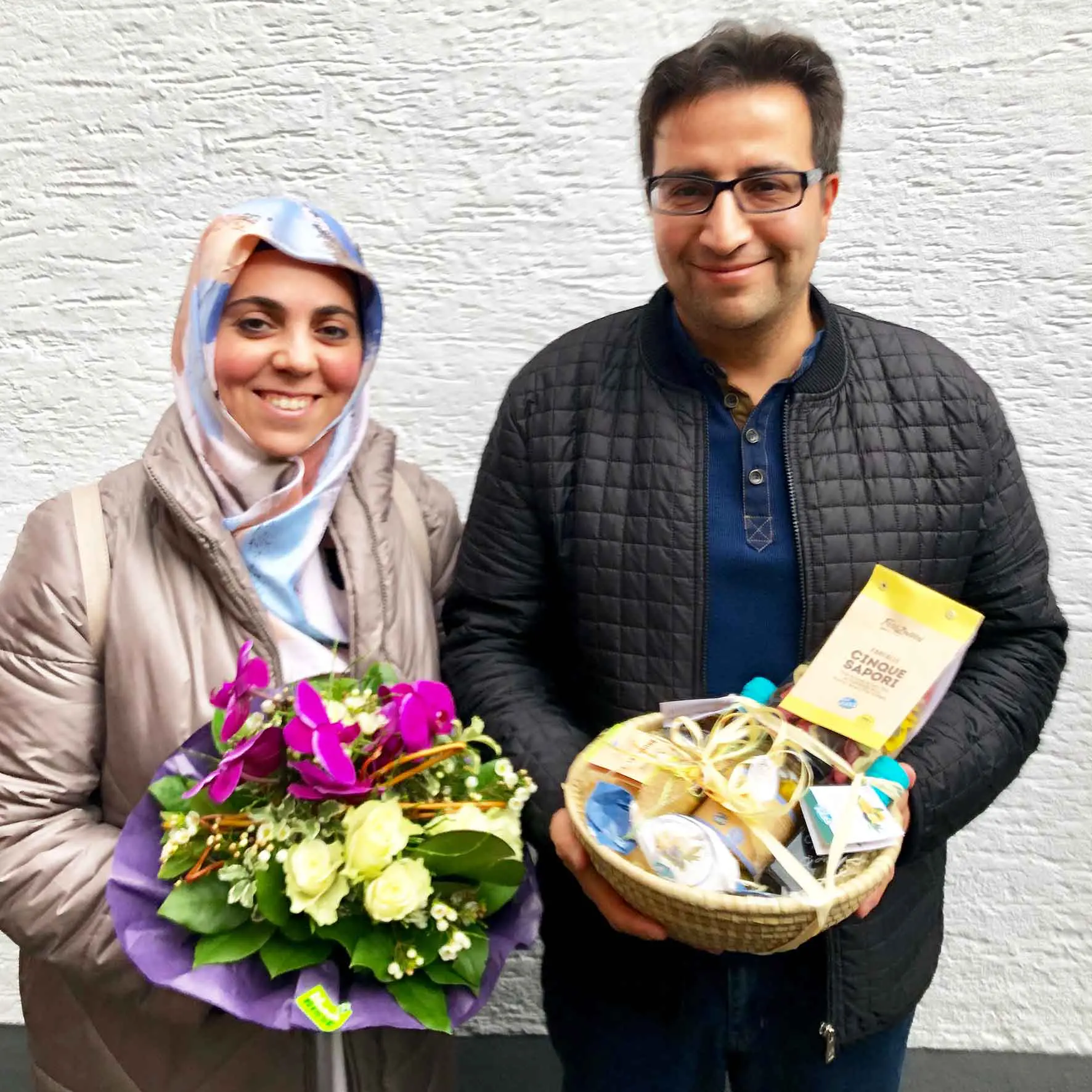 Zufriedene Immobilieneigentümer in Köln Immobilienmakler Köln nach erfolgreichem Notartermin mit überreichtem Blumenstrauß und Geschenkekorb