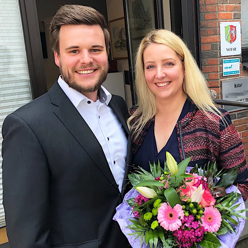Zufriedene Immobilieneigentümer in Köln Merheim nach erfolgreichem Notartermin mit überreichtem Blumenstrauß