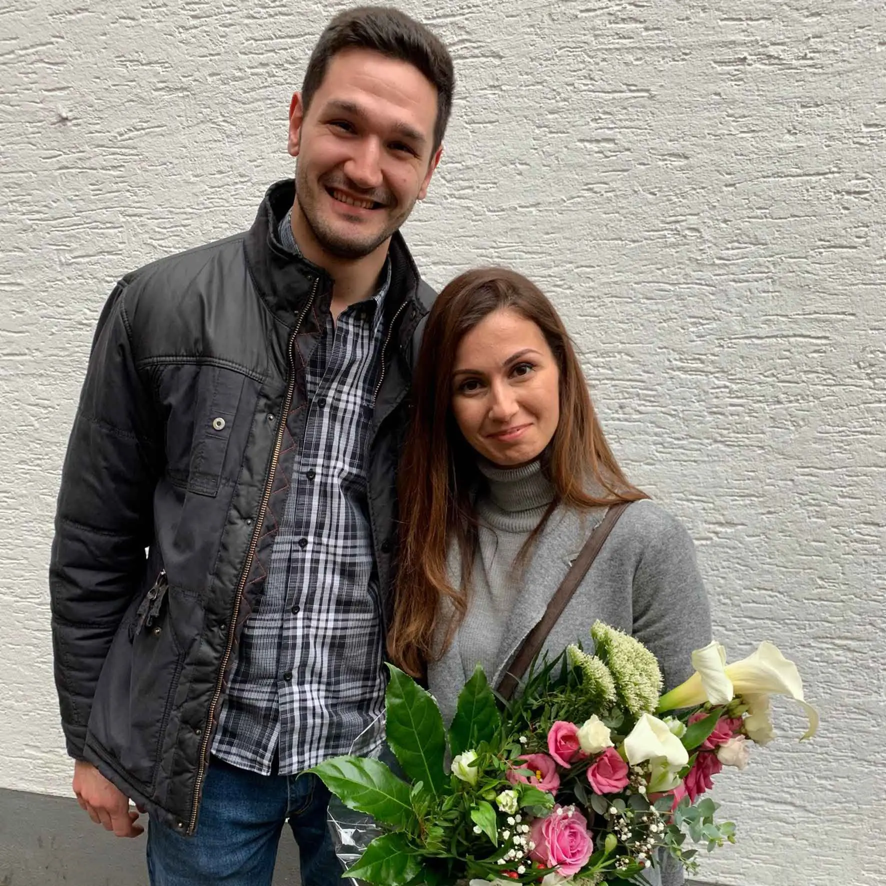 Zufriedene Immobilieneigentümer in Köln Immobilienmakler Köln nach erfolgreichem Notartermin mit überreichtem Blumenstrauß